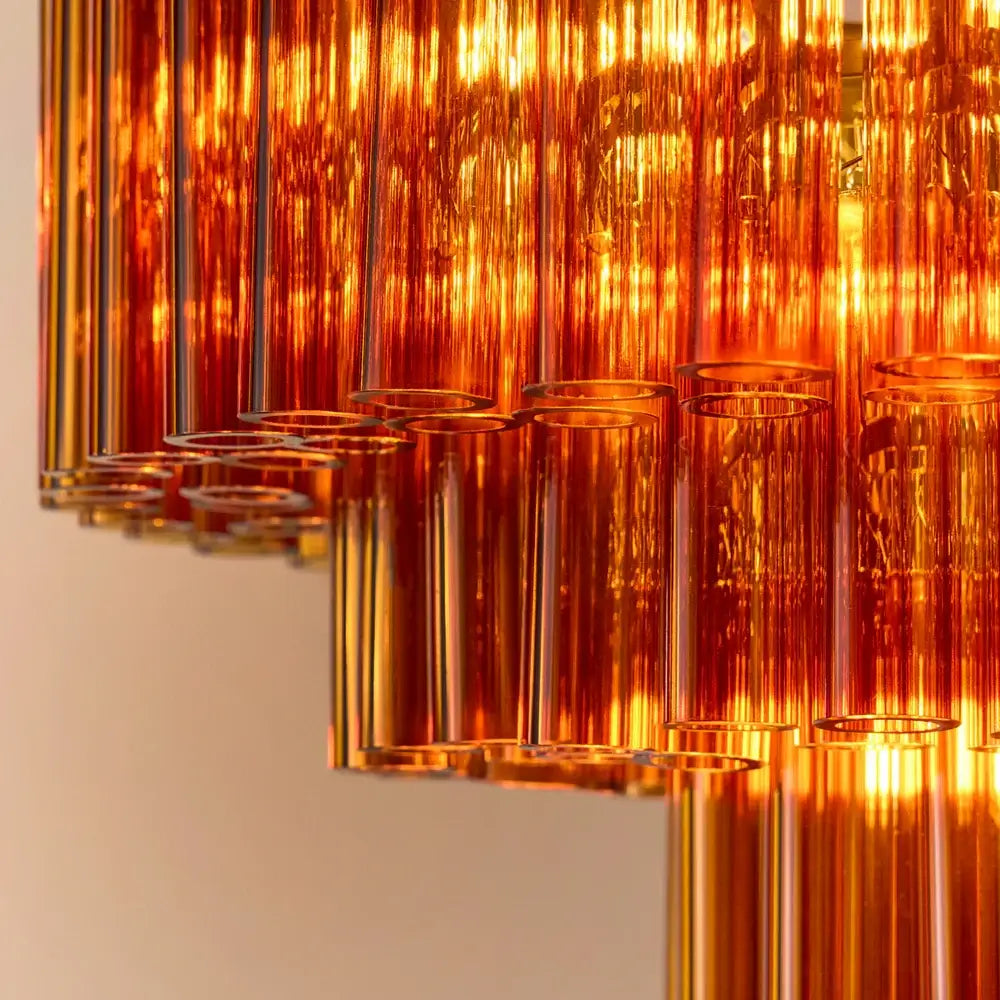Pooky Chiara Chandelier in Amber Glass showcasing warm amber glass tubes and brass fittings creating a rich glow.