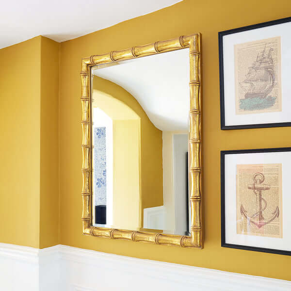 Pooky - Baloo Mirror - Gold Finish mounted on a wall with yellow paint and framed art.