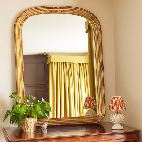 Pooky - Benedict Mirror - Gold Wood displayed over a dresser with elegant curved frame and yellow drapes in the background.