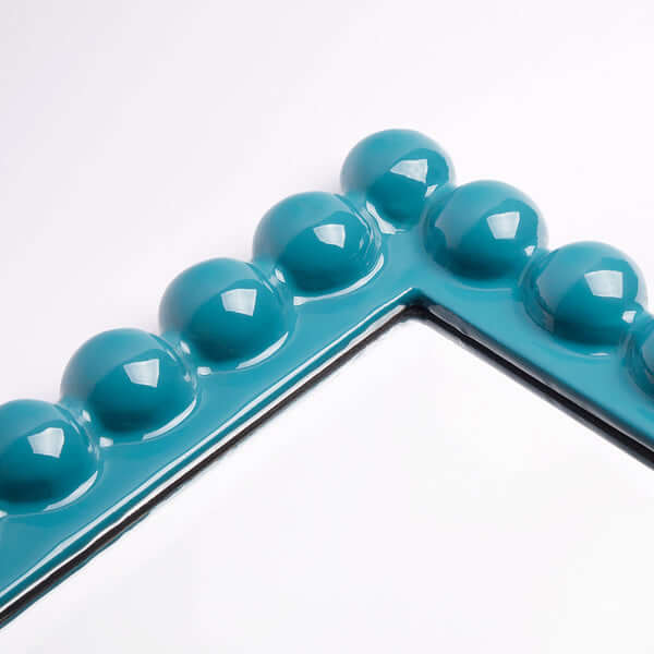 Close-up of the turquoise frame of the Pooky - Charming Mirror - Turquoise showcasing its playful design.