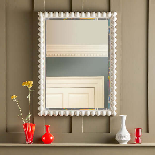 Pooky - Charming Mirror - White showcased on a wall with colorful vases and flowers, emphasizing its playful design.