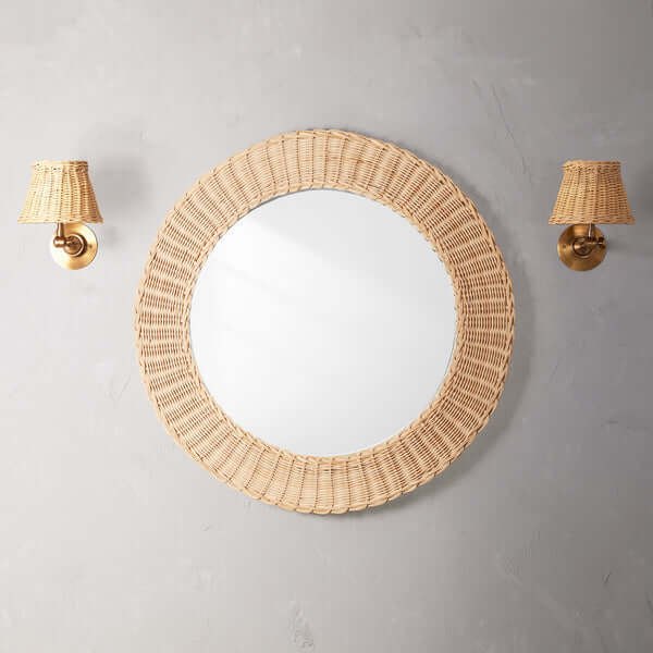 Pooky - Chui Mirror - Natural Woven Cane displayed with duo wall sconces against a textured wall.