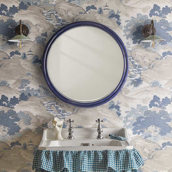 Pooky - Smaller Cinders Mirror - Blue displayed above a vintage sink with a decorative blue wallpaper.