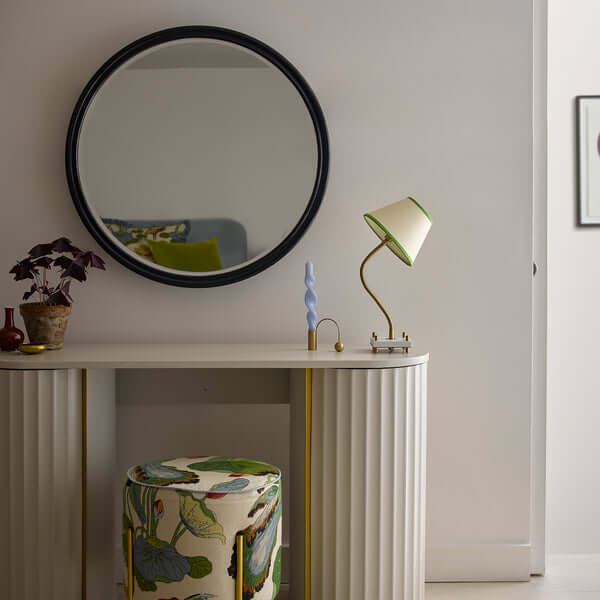 Pooky - Larger Cinders Mirror - Blue above a decorative console table with modern lamp and colorful stool.