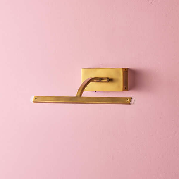 Pooky - Smaller Blake Rechargeable Picture Light - Brass mounted on a pink wall, showcasing its elegant design.