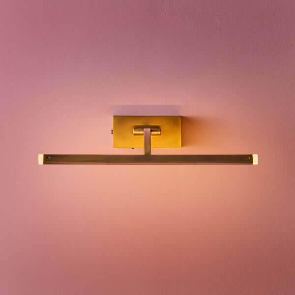 Pooky - Regular Blake Rechargeable Picture Light - Brass mounted on a pink wall, showcasing its elegant design.