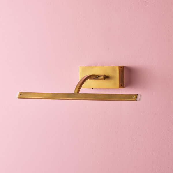 Pooky - Regular Blake Rechargeable Picture Light - Brass mounted on a pink wall, showcasing elegant warm antique brass design.