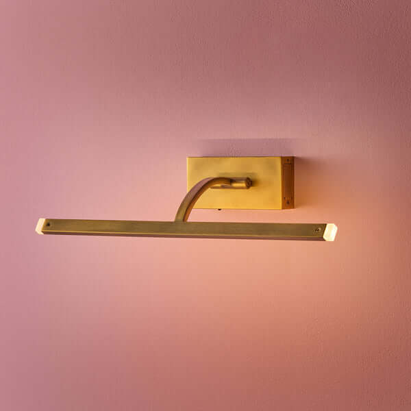 Pooky - Regular Blake Rechargeable Picture Light - Brass mounted on a pink wall, showcasing its elegant design.