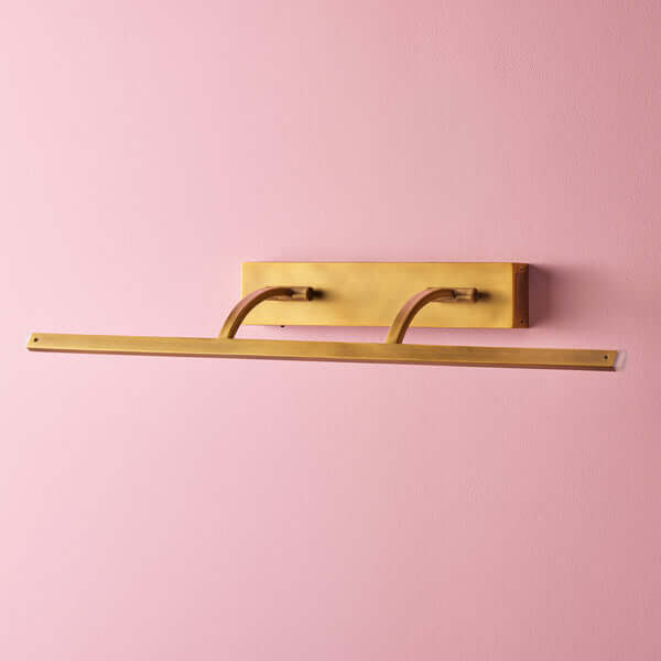 Pooky - Larger Blake Rechargeable Picture Light - Brass mounted on a pink wall, showcasing its elegant design.