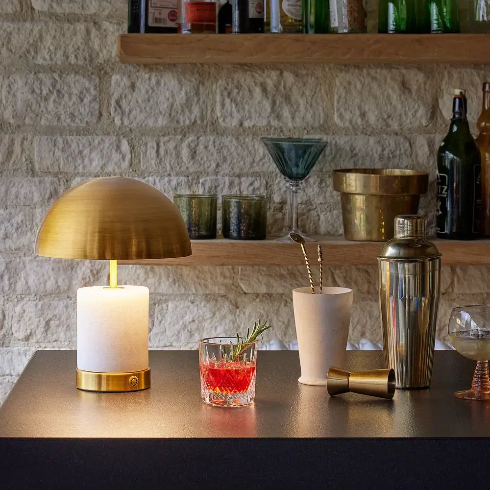 SALE - Pooky Utopia Rechargeable Table Lamp in White Marble illuminating a stylish bar setting.