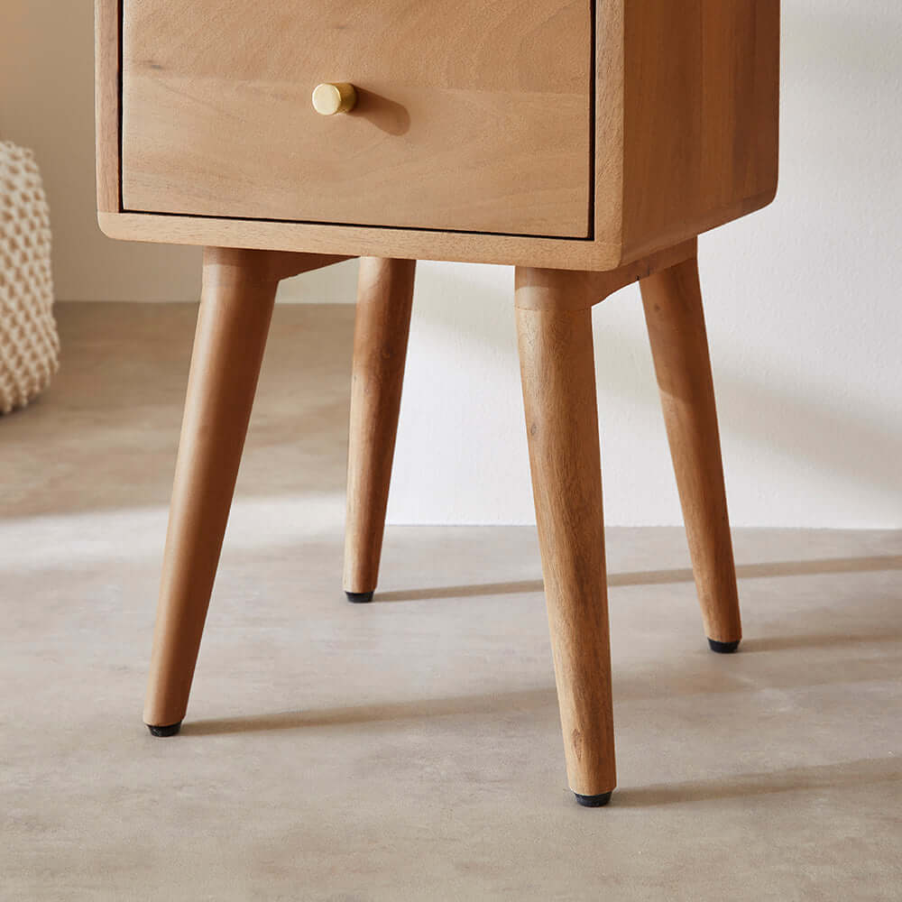 Close-up of the Fishe & Lilly Scandinavian Light Walnut Logan Narrow Bedside Table showing wooden legs and brass pull.