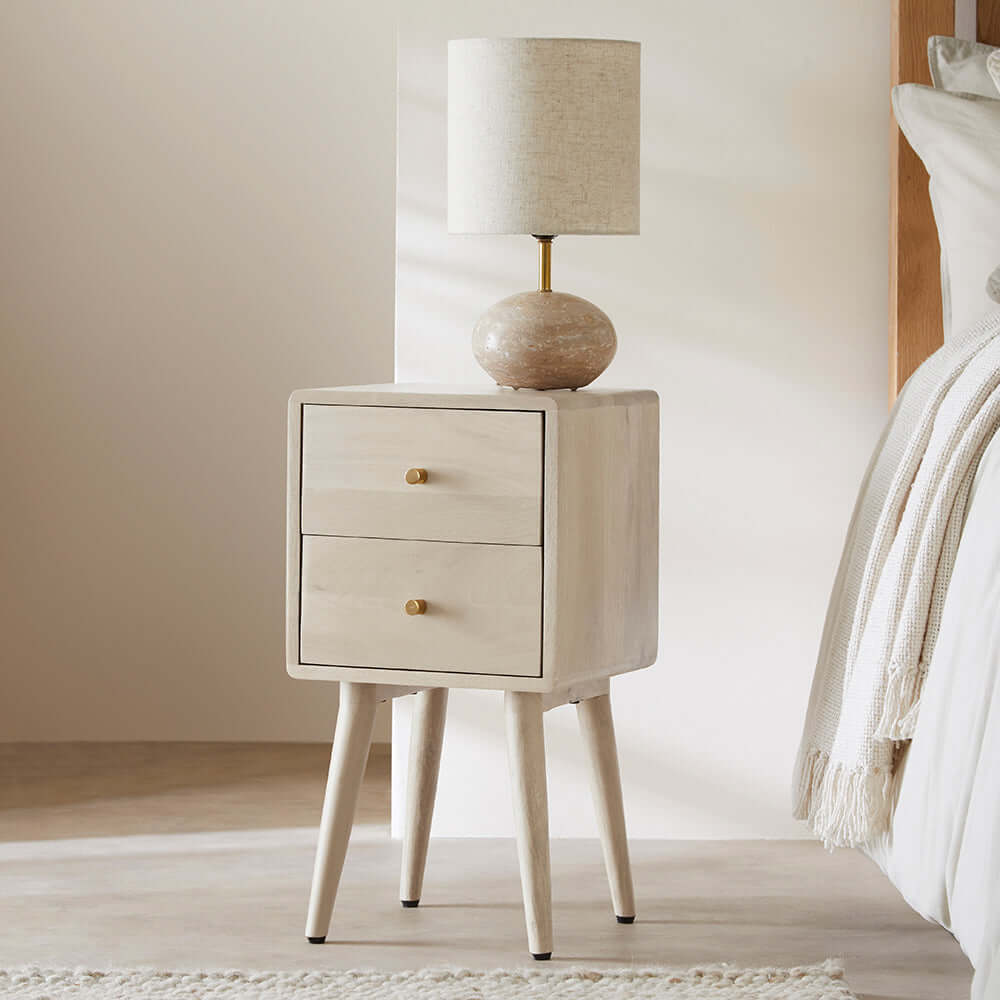 Fishe & Lilly Minimalist Mango Wood White Logan Narrow Bedside Table with two drawers next to a bed.