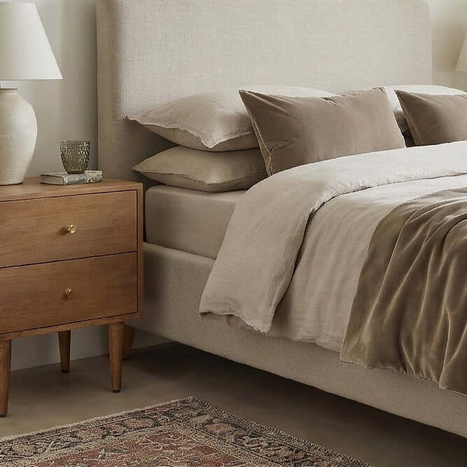 Fishe & Lilly Scandinavian Light Walnut Oslo Bedside Table with two drawers and brass pulls next to a modern bed.