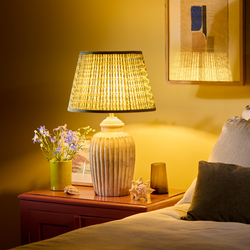 Pooky - Smaller Marcie Table Lamp Base - Natural Whitewash lit on a bedside table next to a bed.