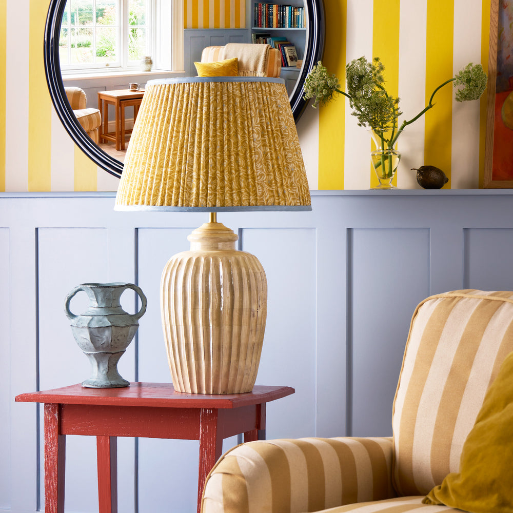 Pooky - Larger Marcie Table Lamp Base - Natural Whitewash styled on a red side table with a patterned yellow lampshade.