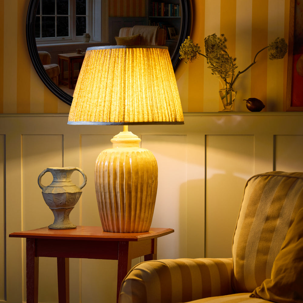 Pooky - Larger Marcie Table Lamp Base - Natural Whitewash with a pleated shade on a wooden side table.