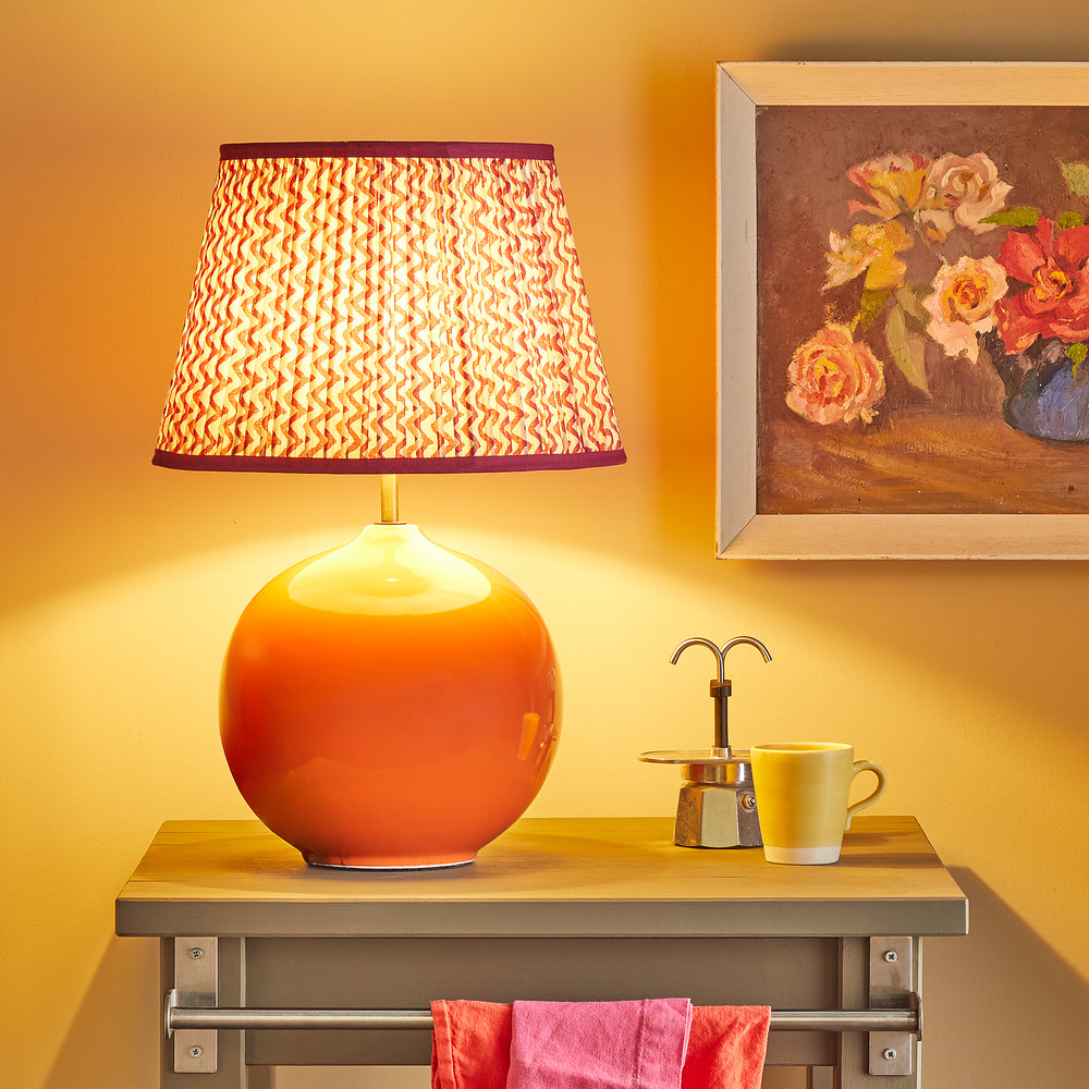 Pooky - Olly Table Lamp Base - Orange with a patterned shade on a side table.