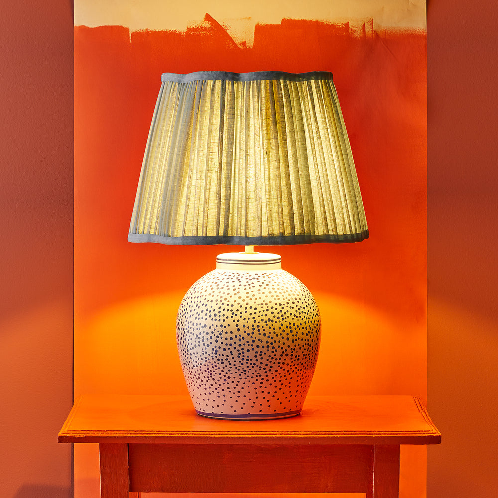 Pooky - Polka Table Lamp Base - Blue and White ceramic lamp with a pleated shade on an orange table.