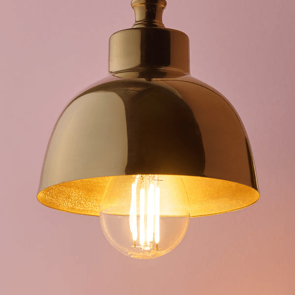 Pooky - Carmel Wall Light - Antiqued Brass Finish showcasing a stylish metal shade with a warm glowing bulb.