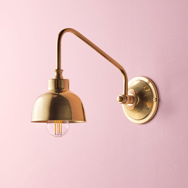 Pooky - Carmel Wall Light - Antiqued Brass Finish mounted on a pink wall, showcasing mid-century design and elegance.