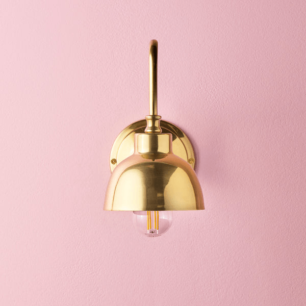 Pooky - Carmel Wall Light - Antiqued Brass Finish mounted on a pink wall, featuring a stylish dome design.