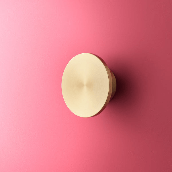 Pooky - Helios Ip44 Wall Light - Smaller - Brushed Gold Aluminium mounted on a pink wall.