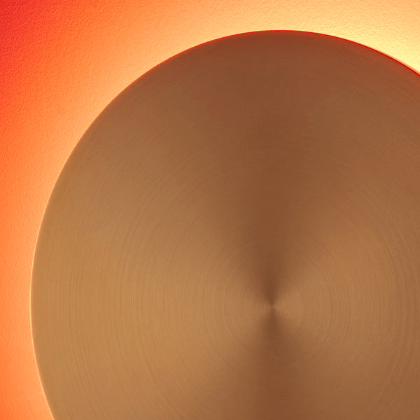 Pooky - Helios Ip44 Wall Light - Larger - Brushed Gold Aluminium glowing against a warm-colored wall.