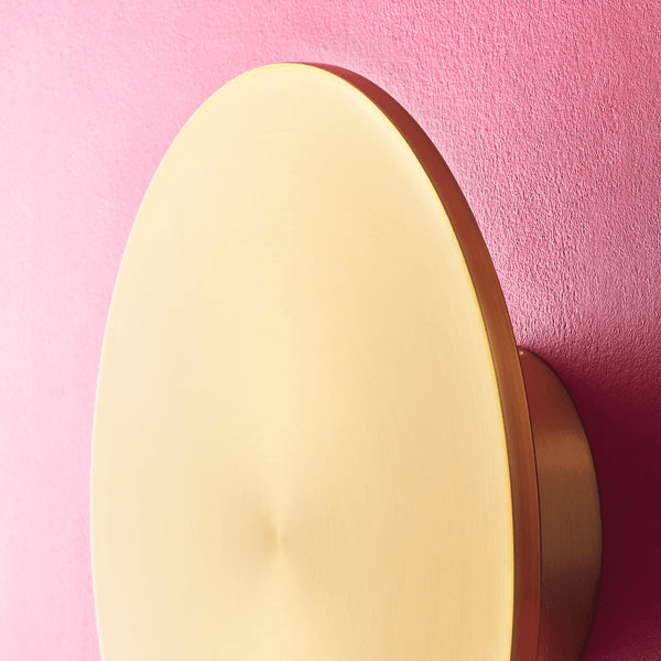 Pooky - Helios Ip44 Wall Light - Larger - Brushed Gold Aluminium mounted on a pink wall.