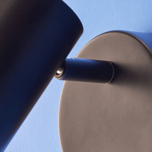 Pooky - Lewis single Wall Light - Black - With switch mounted on a blue wall, showcasing its adjustable design.