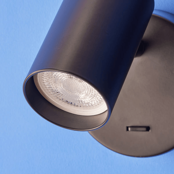 Pooky - Lewis single Wall Light - Black - With switch mounted on wall, spotlight beam directed for illumination.