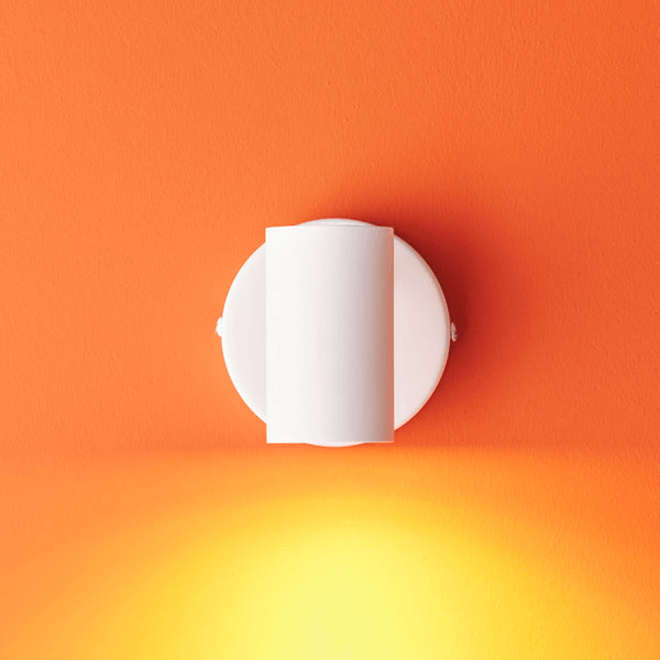 Pooky - Lewis single Wall Light - White - With switch mounted on an orange wall, illuminating the space below.
