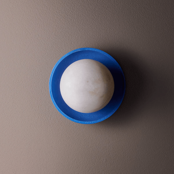Pooky - Luna Wall Light - Klein Blue mounted on a wall, featuring a white alabaster globe and a blue ceramic dish.