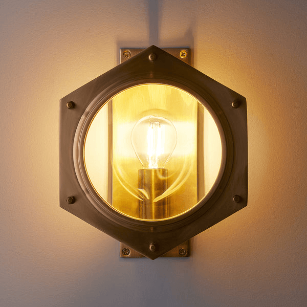 Pooky - Poirot Wall Light - Brass And Glass featuring a hexagonal design and warm glowing bulb.