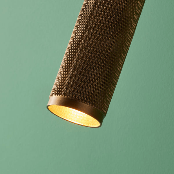 Pooky - Quantum Single Wall Light - Antiqued Brass with knurled texture illuminating a green wall.