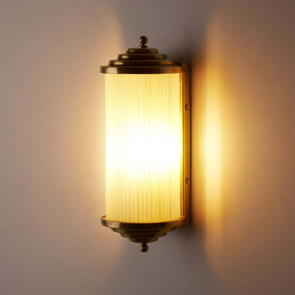 Pooky - Deco Baby Roddy ip44 Rated Wall Light - Brass and Frosted Glass elegantly illuminating a wall.
