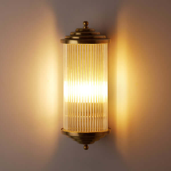 Pooky - Deco Baby Roddy ip44 Rated Wall Light - Brass and Glass illuminating a wall with elegant design.
