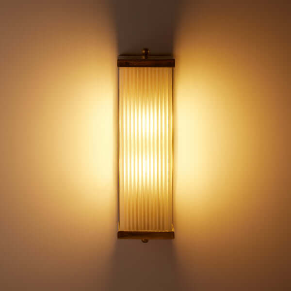 Pooky - Rectangular Roddy ip44 Rated Wall Light - Brass and Frosted Glass illuminating a wall with warm light.