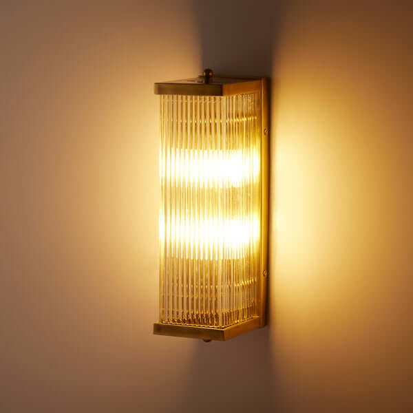 Pooky - Rectangular Roddy ip44 Rated Wall Light - Brass and Glass illuminated on a wall.