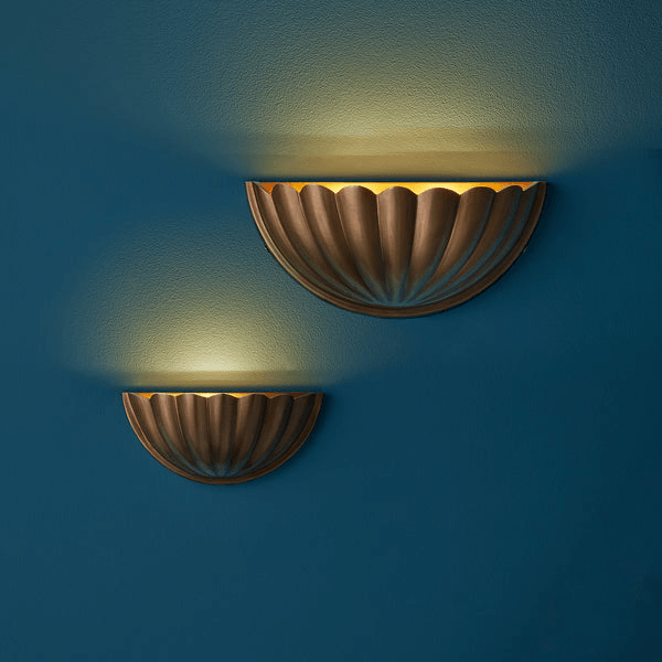Pooky - St Jacques Wall Light - Smaller - Brass wall sconces against a blue wall, showcasing scallop shell design.