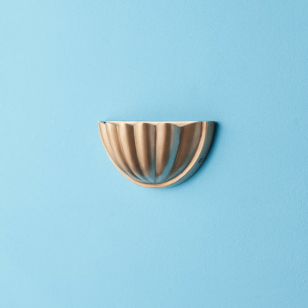 Pooky - St Jacques Wall Light - Smaller - Brass mounted on a blue wall, showcasing its scallop shell design.