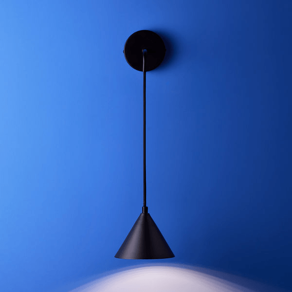 Pooky - Sway Wall Light - Black hanging on a blue wall, showcasing a sleek black conical design.