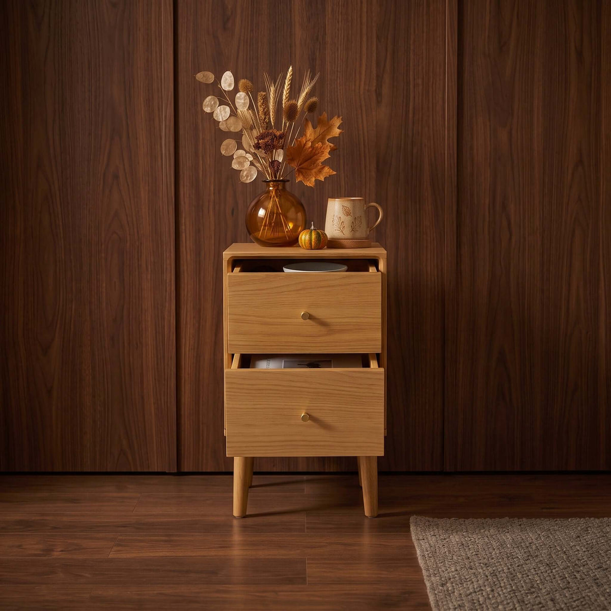 Fishe & Lilly Wright Narrow Oak Bedside Table with two open drawers, styled with a floral vase and mug on top.