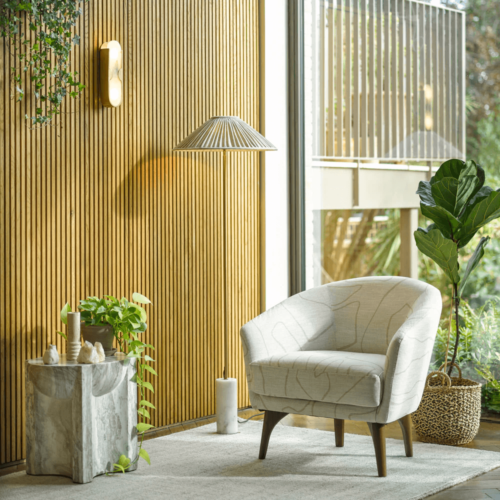 Pooky - Epicurus Alabaster Wall Light illuminating a stylish living space with a comfortable chair and greenery.
