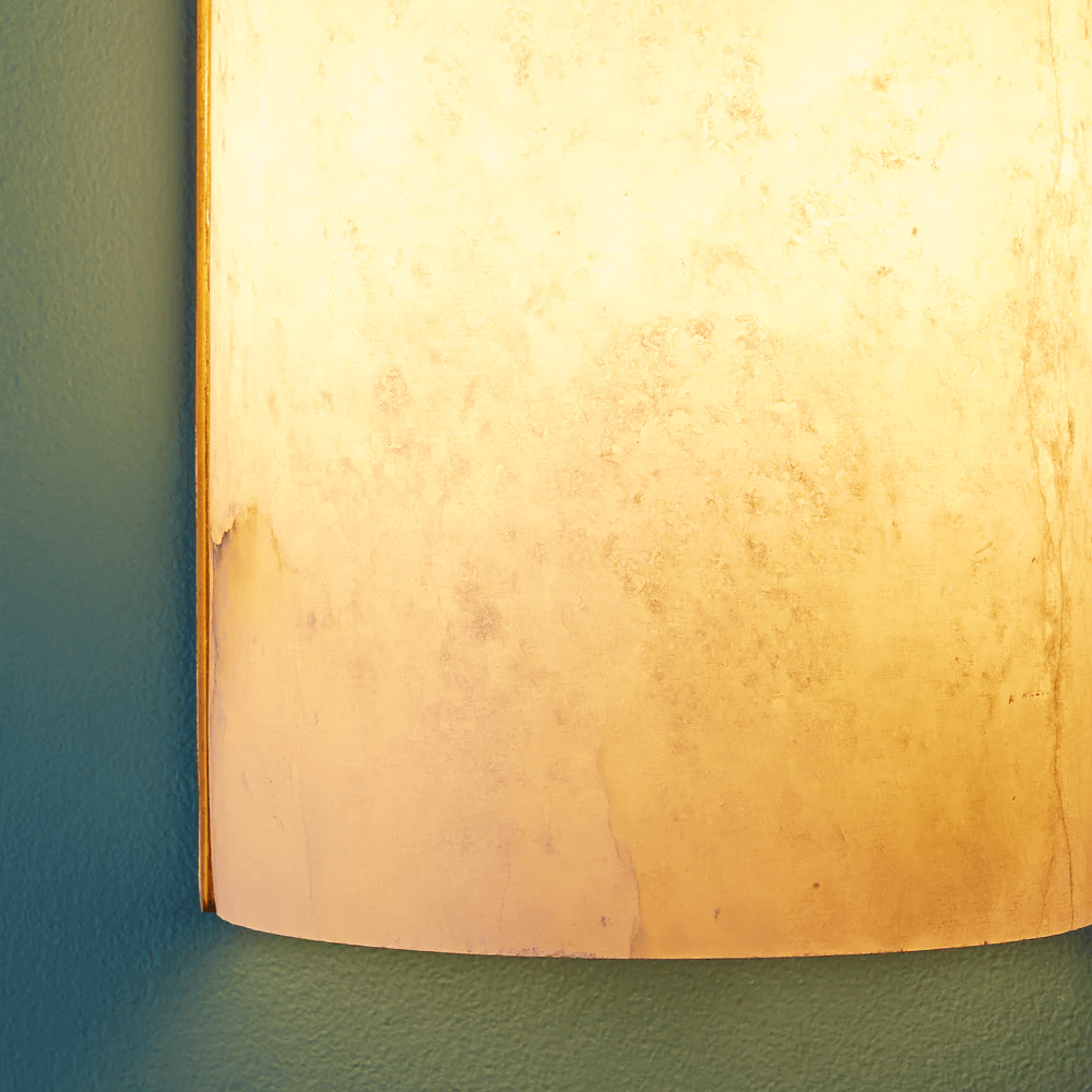 Pooky - Zeno Alabaster Wall Light illuminating textured alabaster surface on a green wall.