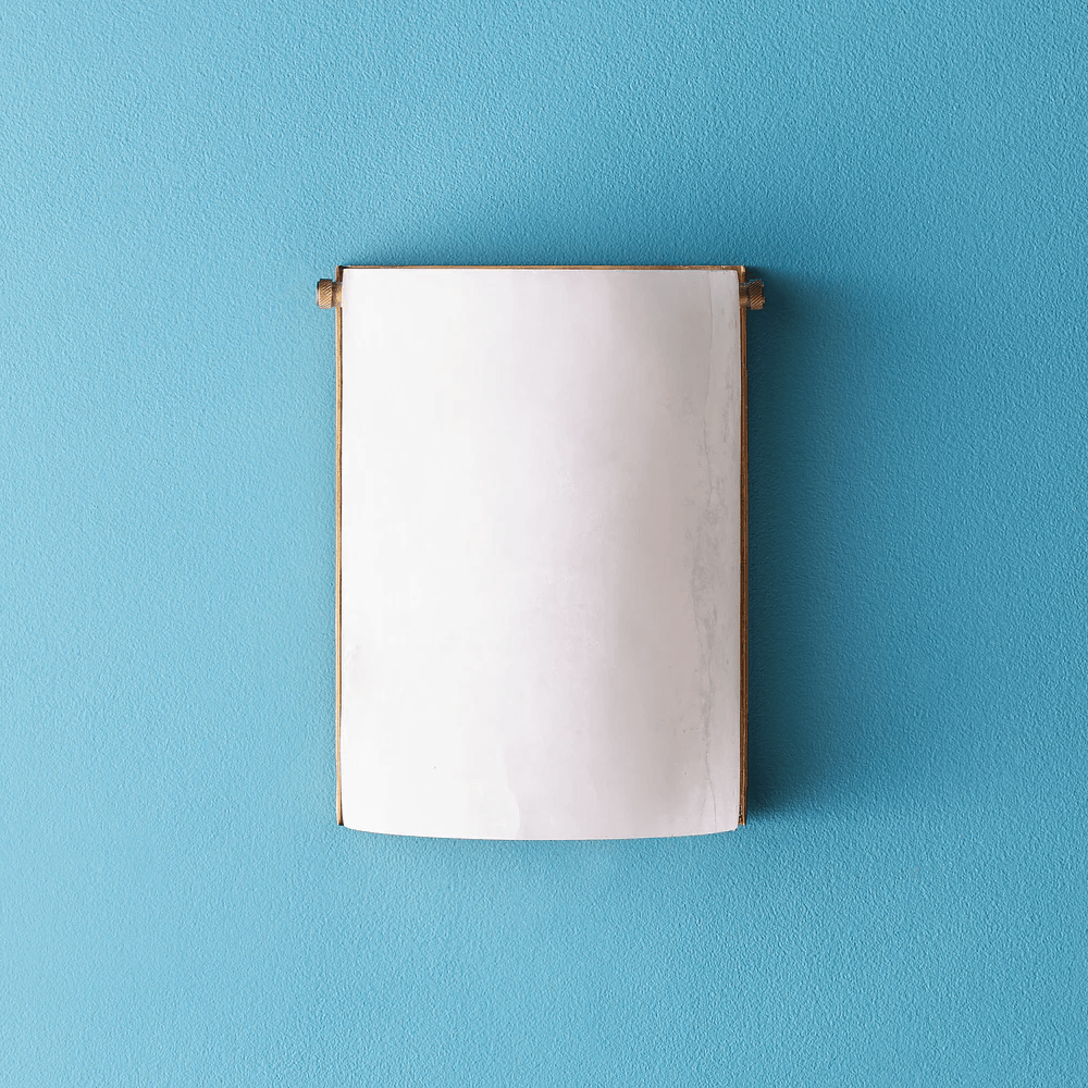 Pooky - Zeno Alabaster Wall Light mounted on a blue wall, showcasing its elegant design and natural material.