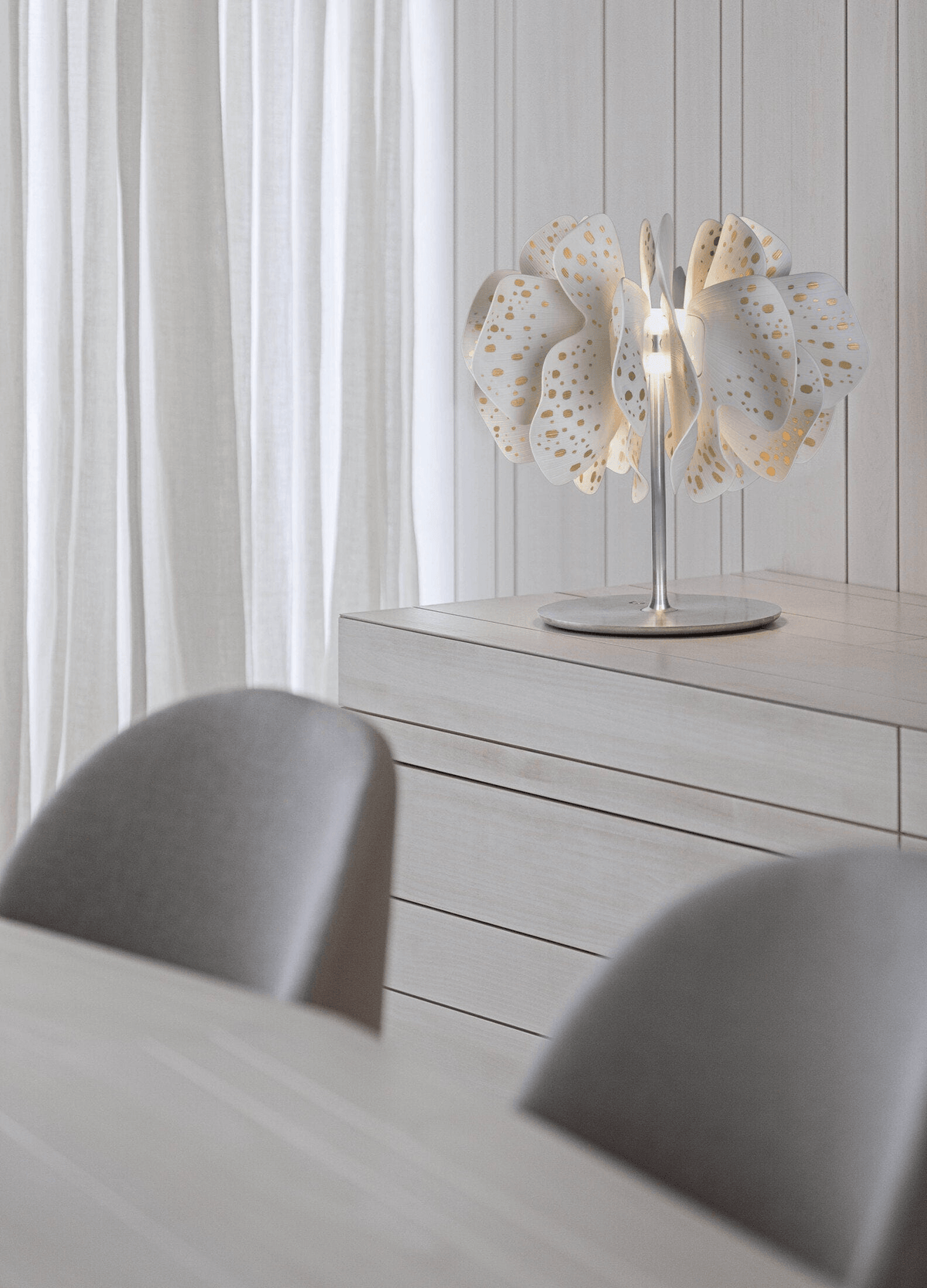 Lladró - Nightbloom Table Lamp - Golden Luster made of Lladro Porcelain, featuring glowing organic petals on a white dresser.