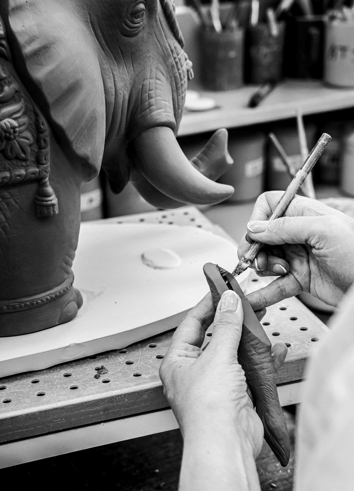 Craftsmanship process of Lladró - Siamese Elephant Table Lamp featuring an artist sculpting in clay.