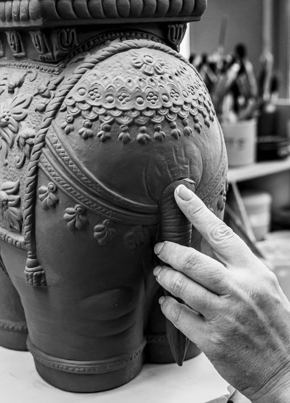Close-up of artisan's hand detailing the Lladró - Siamese Elephant Table Lamp sculpture in clay.