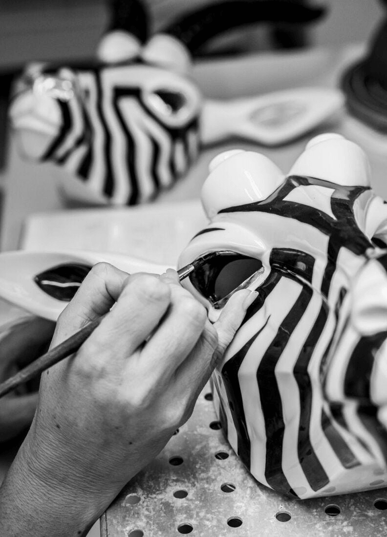 Artist painting details on Lladró Black and Gold Antelope Mask porcelain creation.