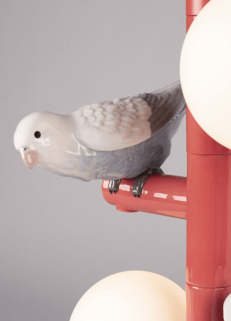 Lladró - Parrot Table Lamp - Red with detailed porcelain bird perched on a vibrant coral structure.